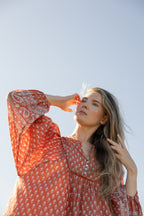 Made by Mortals women’s Desert Bloom Midi Dress in rust with billowy sleeves, hand block printed cotton bohemian dress by artisans in India.