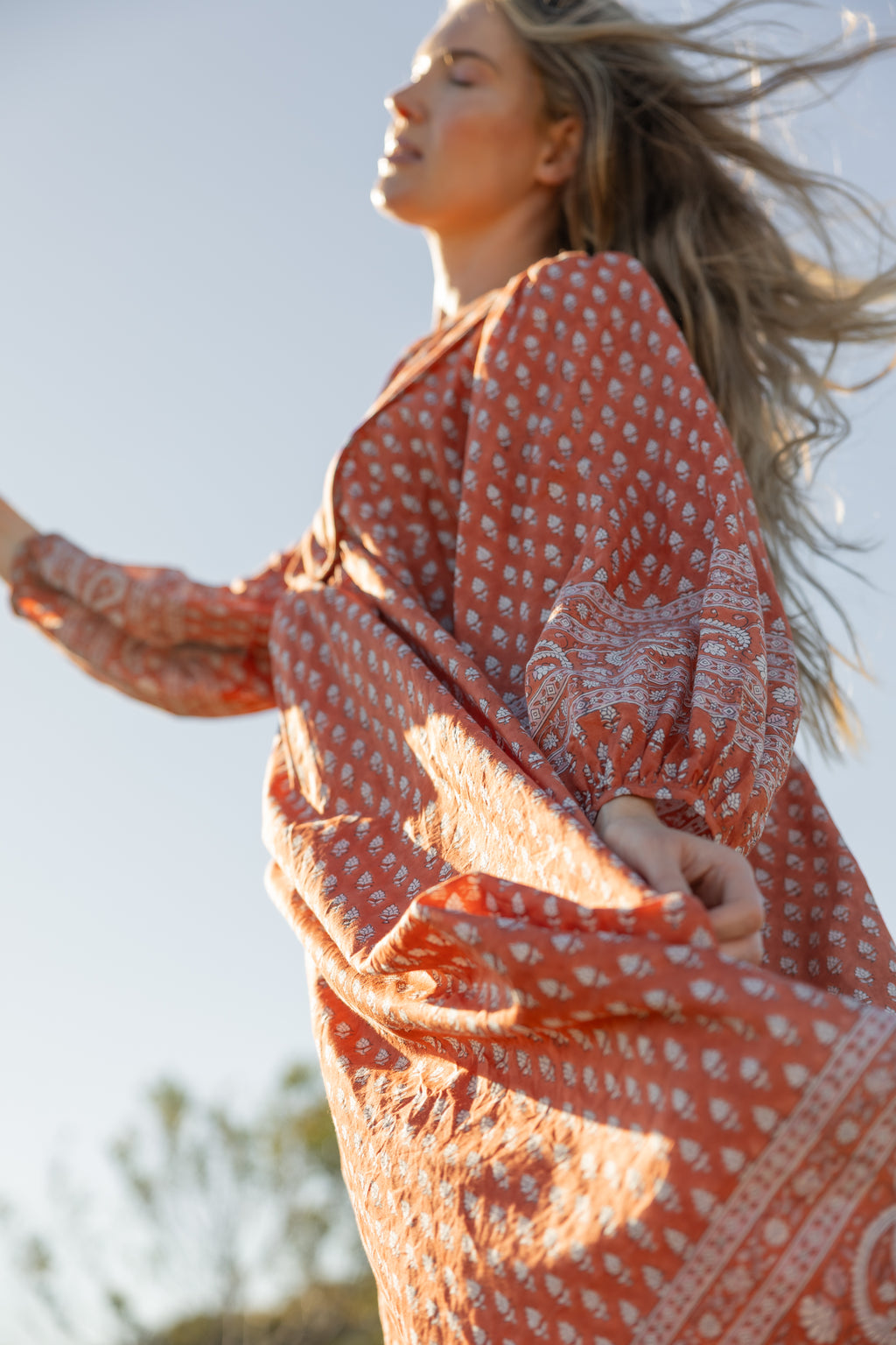 Made by Mortals women’s Desert Bloom Midi Dress in rust with billowy sleeves, hand block printed cotton bohemian dress by artisans in India.