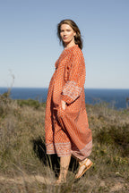 Made by Mortals women’s Desert Bloom Midi Dress in rust with billowy sleeves, hand block printed cotton bohemian dress by artisans in India.