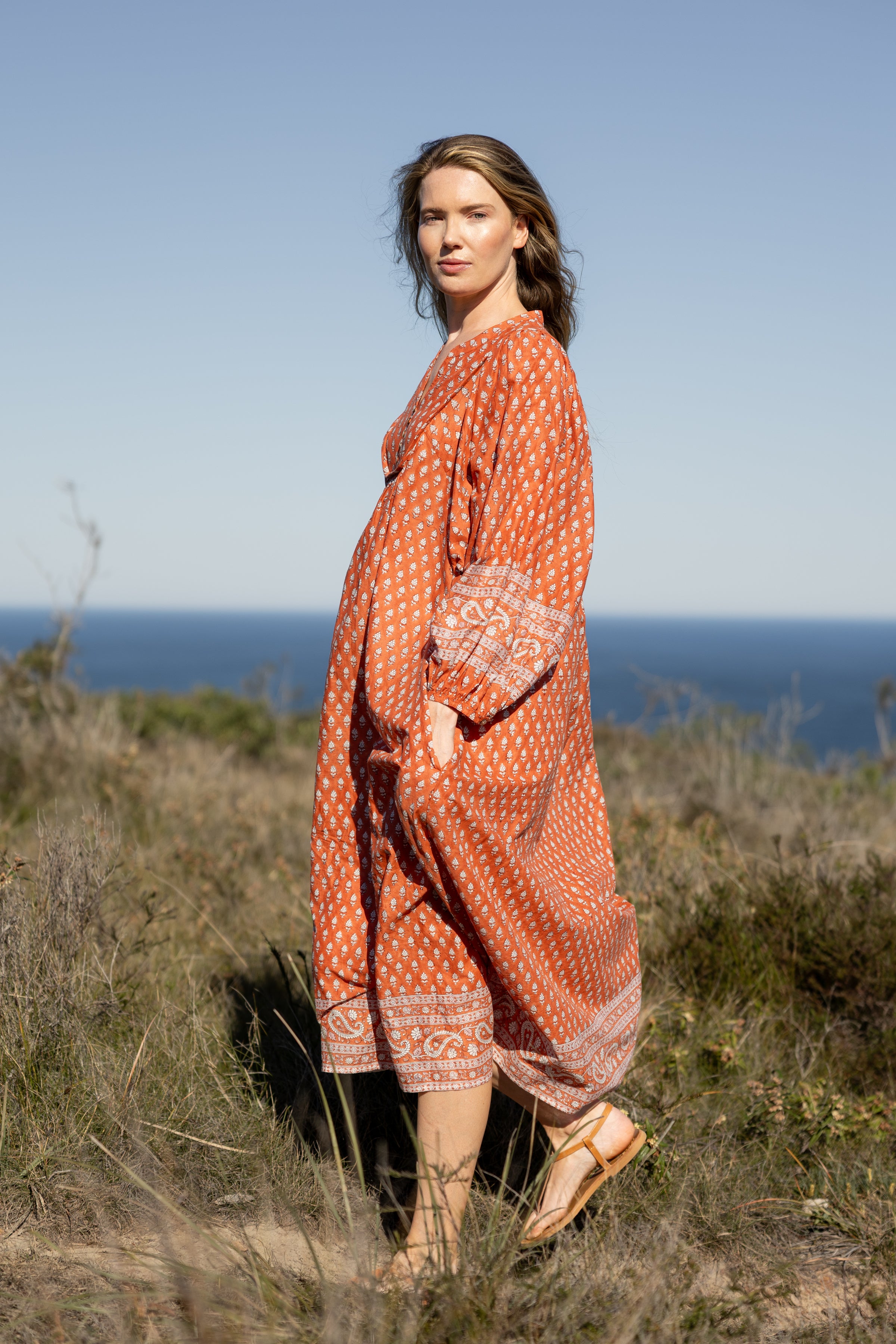 Made by Mortals women’s Desert Bloom Midi Dress in rust with billowy sleeves, hand block printed cotton bohemian dress by artisans in India.