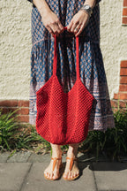 Sorrento Crochet Tote, a lightweight cotton crochet bag in red worn with a hand block print cotton dress.