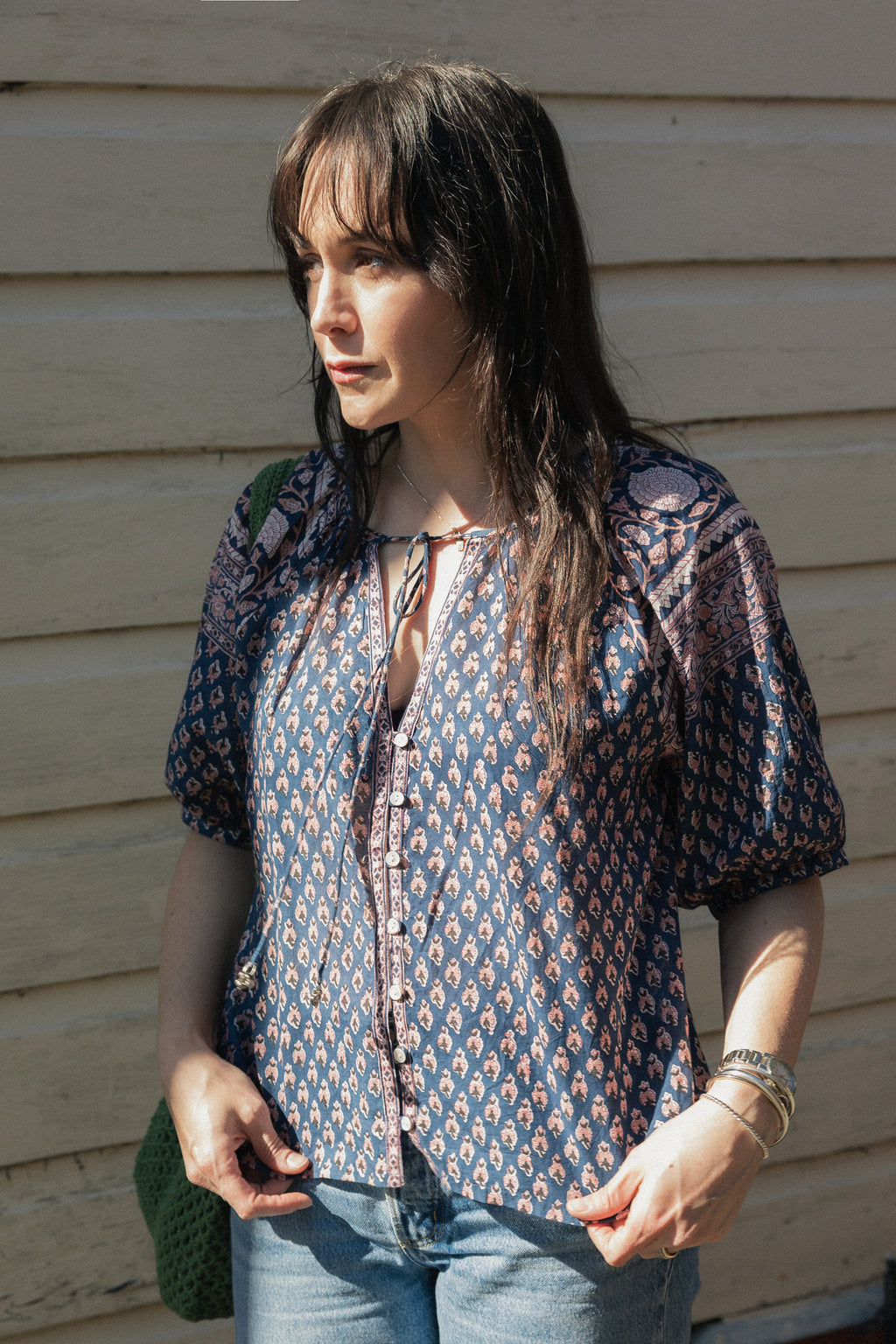 Woman standing in sun  wearing the Lisette navy hand block printed blouse with jeans.
