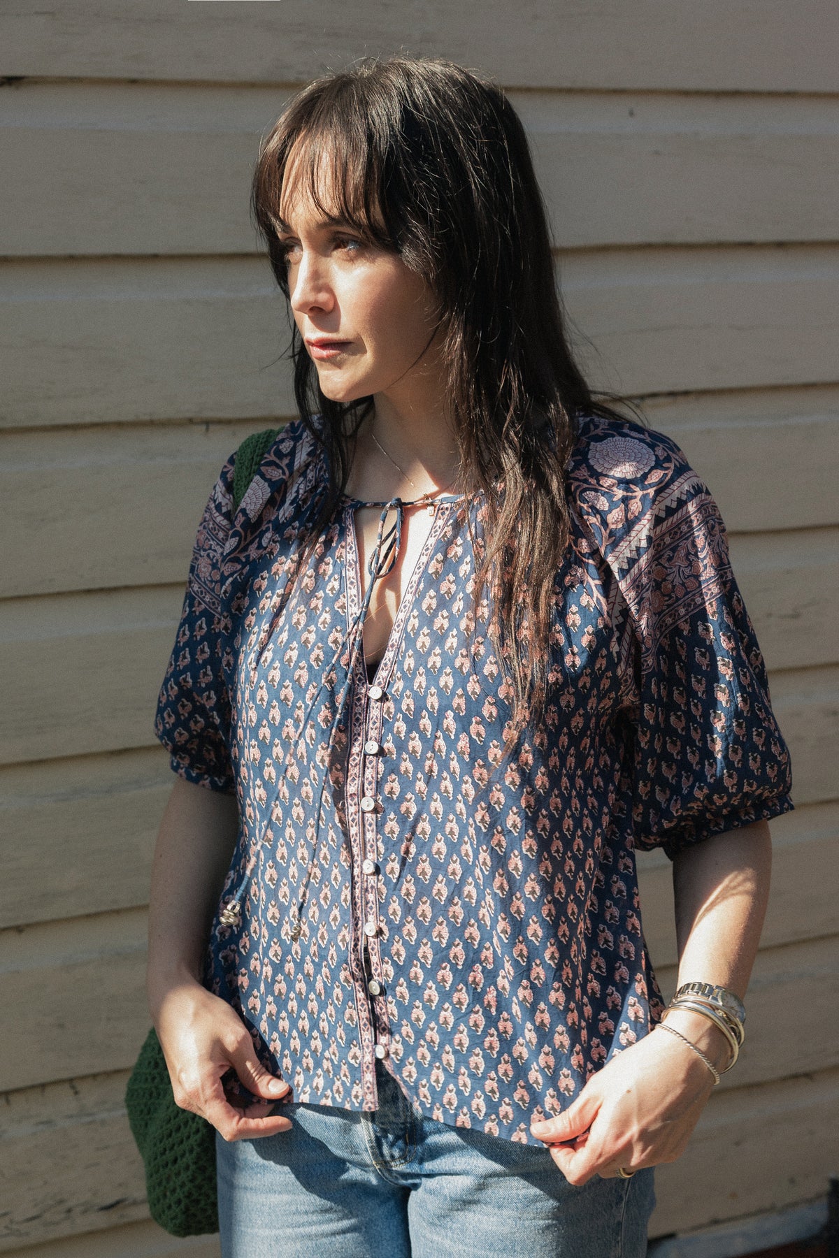 Woman standing in sun  wearing the Lisette navy hand block printed blouse with jeans.
