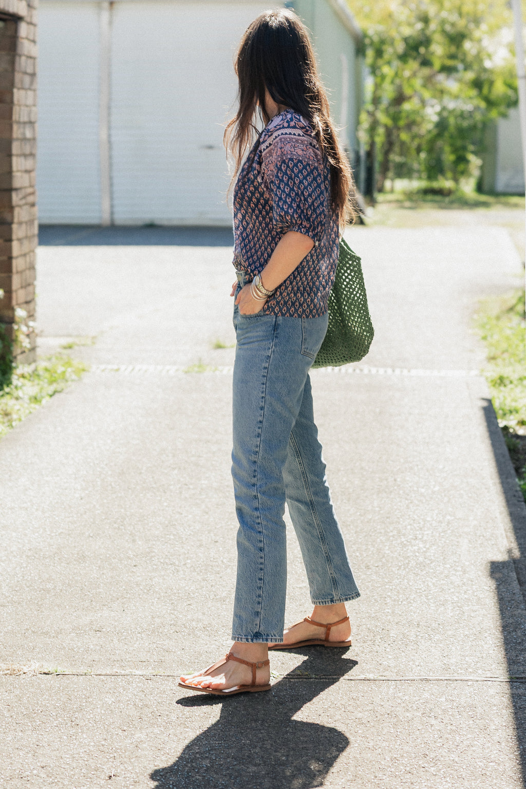 Woman walking in sun wearing the Lisette navy hand block printed blouse with jeans.
