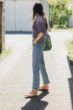 Woman walking in sun wearing the Lisette navy hand block printed blouse with jeans.