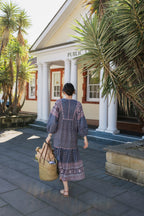 Woman walking with basket wearing the Lisette Midi Dress, a navy and soft nude hand block print cotton midi dress.