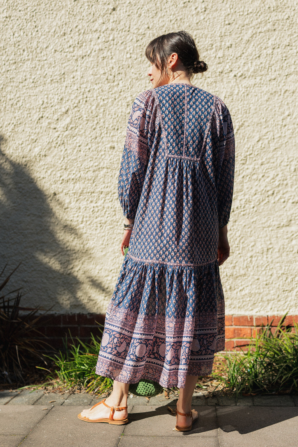Woman against wall wearing the Lisette Midi Dress, a navy and soft nude hand block print cotton midi dress.