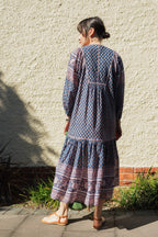 Woman against wall wearing the Lisette Midi Dress, a navy and soft nude hand block print cotton midi dress.