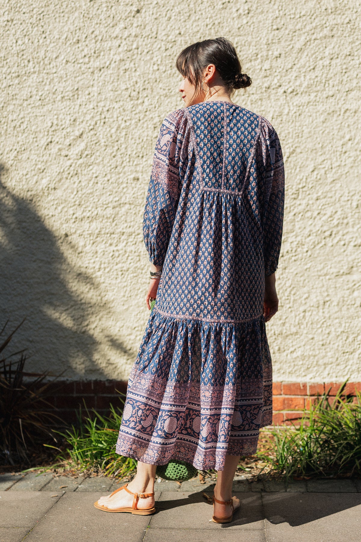 Woman against wall wearing the Lisette Midi Dress, a navy and soft nude hand block print cotton midi dress.