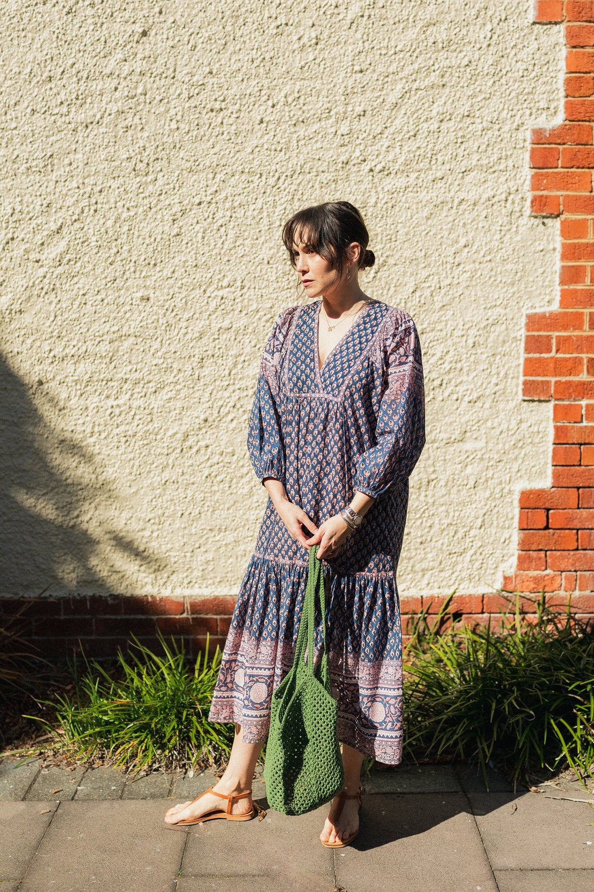 Woman against wall wearing the Lisette Midi Dress, a navy and soft nude hand block print cotton midi dress. 