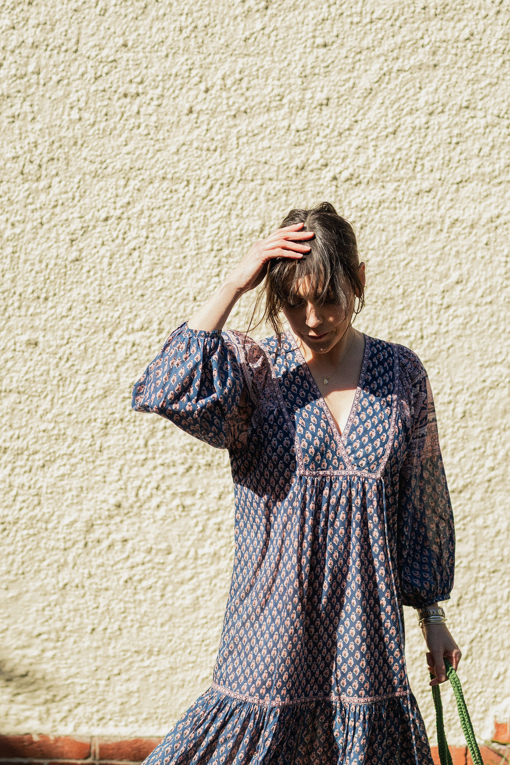 Woman against wall in sun wearing the Lisette Midi Dress, a navy and soft nude hand block print cotton midi dress.