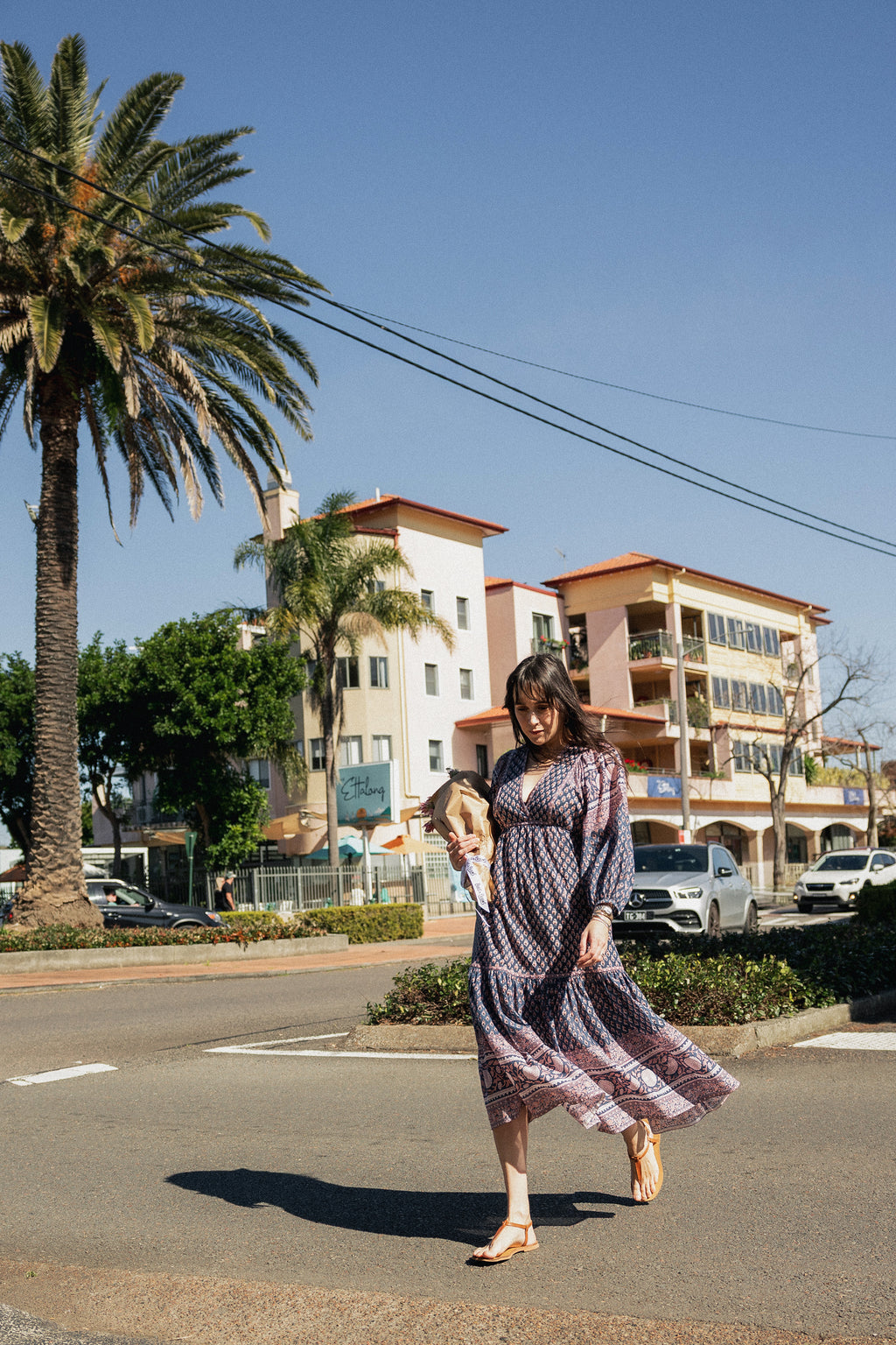 Woman crossing street wearing the Lisette Midi Dress, a navy and soft nude hand block print cotton midi dress.