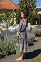 Woman in front white picket fence wearing the Lisette Midi Dress, a navy and soft nude hand block print cotton midi dress.